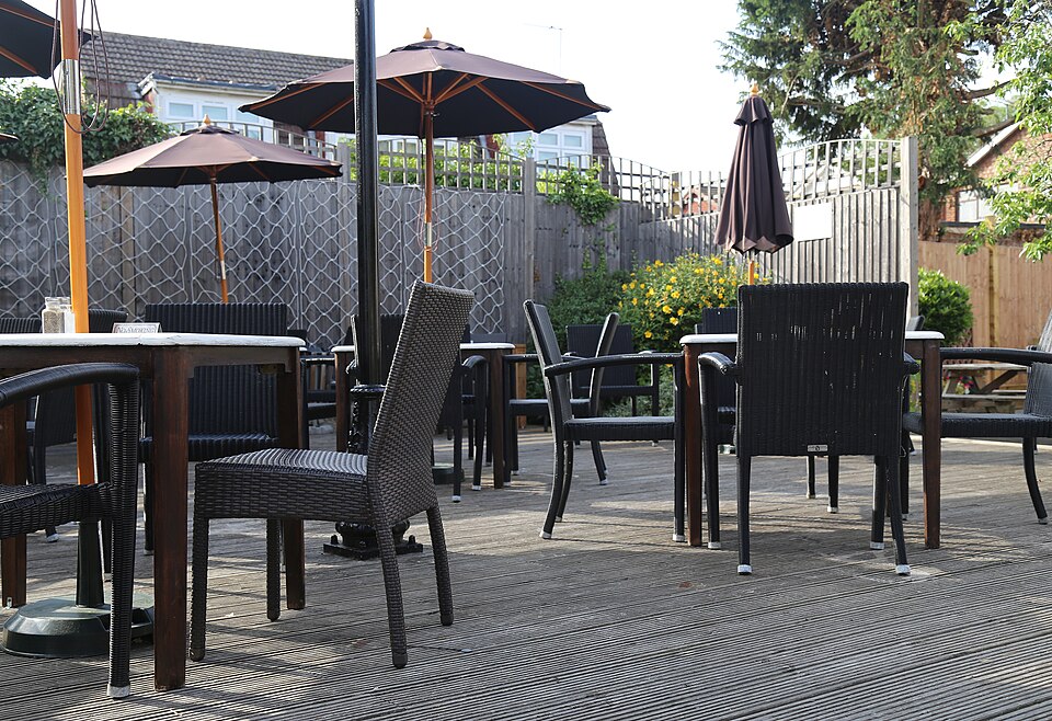 A raised wood decking with outdoor furniture in the beer garden of the Queen Victoria public house at  Theydon Bois, Essex, England